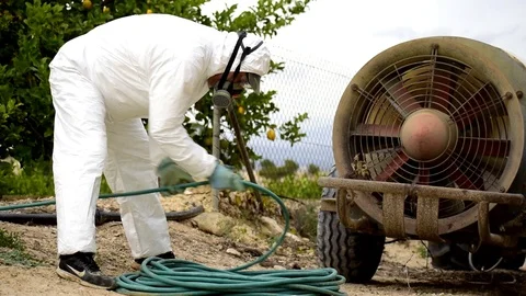 A worker with protective clothes and gloves coiling the hose after fumigation Stockbeeldmateriaal 121411234