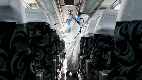 Worker in protective face mask and costume disinfecting the bus interior Video stock 126609503