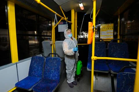 Worker in protective face mask and costume disinfecting the trolley interior Stock Photos