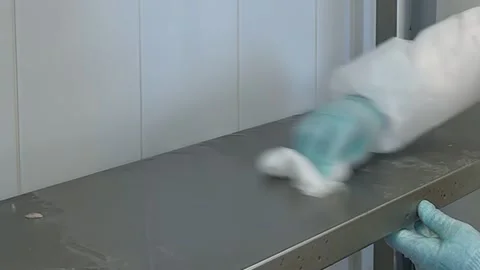 Worker in Protective Gear Cleaning Shelves in a Lab or Factory Stock Footage 320138514