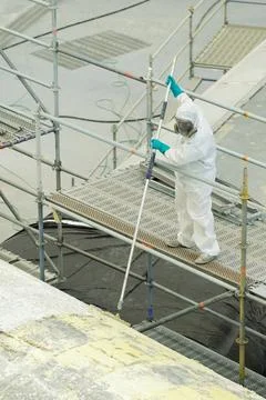 A worker in protective gear cleans paint from the surface at the repair site  Photos