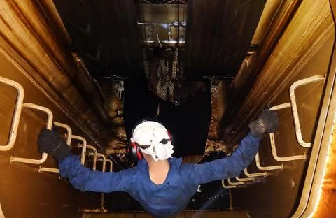 Worker in Protective Gear Descending into Confined Industrial Space Stock Photos