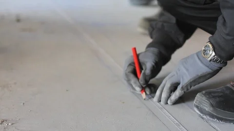 Worker with protective gear marking on the floor with a pencil and tape. 스톡 동영상 99977977