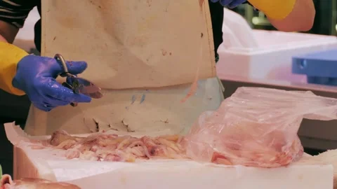 Worker in protective gear processing seafood in industrial setting, ensuring Stock Footage 277417630