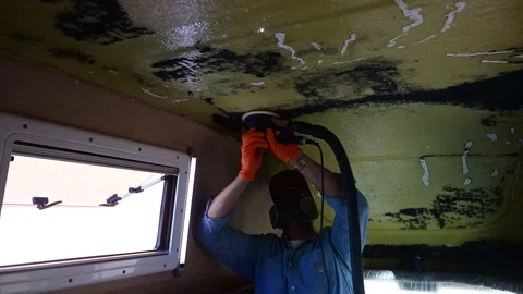 Worker with protective gear sanding the ceiling of a vehicle Stock-Footage 347636872