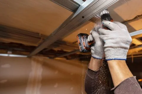 Worker with protective gloves is drilling by perforator the ceiling for Stock Photos