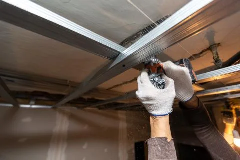 Worker with protective gloves is drilling by perforator the ceiling for Stock Photos