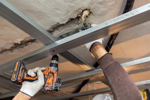 Worker with protective gloves is drilling by perforator the ceiling for Stock Photos