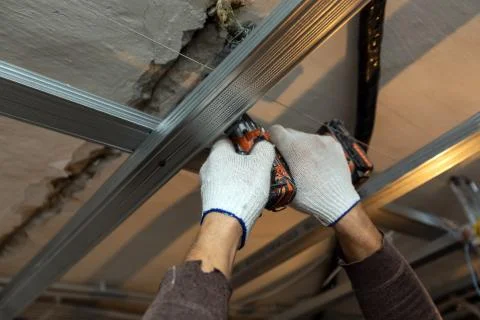 Worker with protective gloves is drilling by perforator the ceiling for Stock Photos