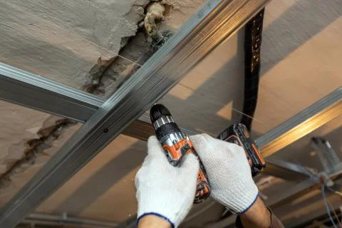 Worker with protective gloves is drilling by perforator the ceiling for Stock Photos