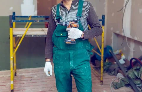 Worker with protective gloves is holdind a perforator with some drywall screws Stock Photos