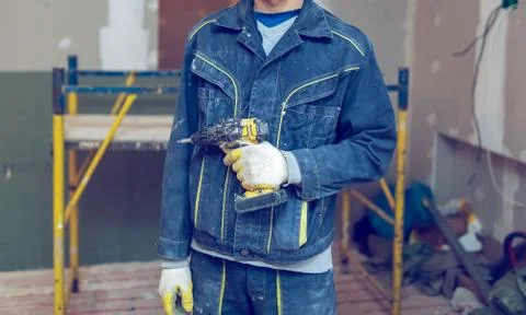 Worker with protective gloves is holdind a perforator with some drywall screws Stock Photos
