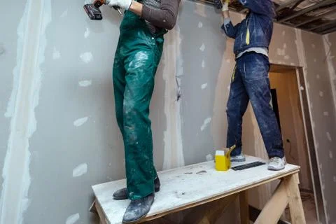 Worker with protective gloves is holdind a perforator with some drywall screws Stock-Fotos