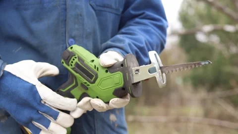 A worker in protective gloves replaces the blade on a sabre saw Stock-Footage 336010335