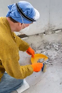 Worker in protective mask and gloves sweeps old tile fragments and construc.. Stock Photos