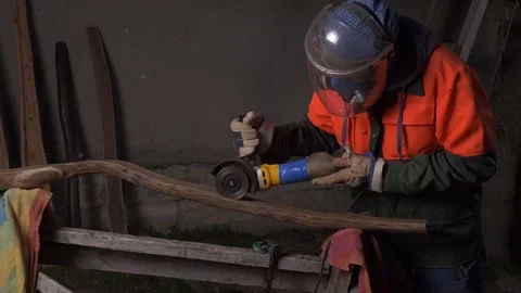 A worker in a protective mask cuts a half of a processed log with an electric Stock Footage 244990194