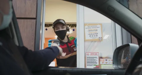 Worker in protective mask issues takeaway order at Burger King Stock Footage 146021884