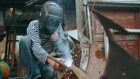 A worker in a protective mask welding metal structures in the backyard. Stock Footage 242992050