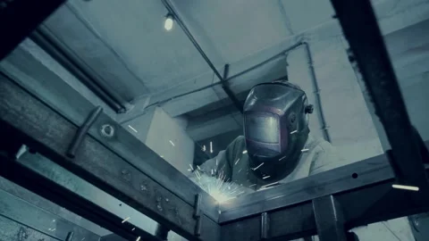 Worker in protective mask welds carcass in workshop low angle Stock Footage 133736101