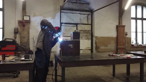 A worker in a protective mask welds metal parts Vídeo Stock 225442579
