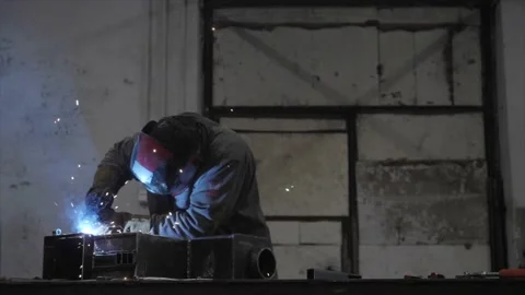 A worker in a protective mask welds metal parts Stockbeeldmateriaal 225442823