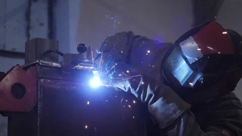 A worker in a protective mask welds metal parts Stockbeeldmateriaal 225768274