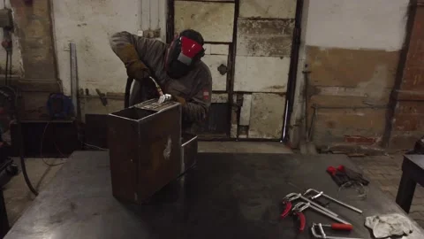 A worker in a protective mask welds metal parts Vídeo Stock 228774769