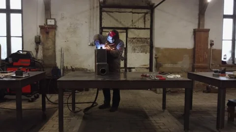 A worker in a protective mask welds metal parts Video stock 228785448