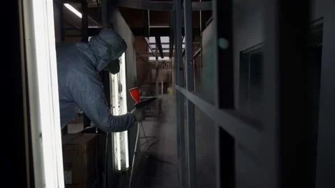 A worker in a protective suit and mask applies a powder layer to metal parts Video stock 166077923