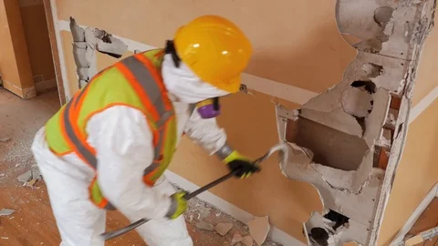 Worker in protective suit demolishes plaster wall. (with Audio) Stock Footage 92590232