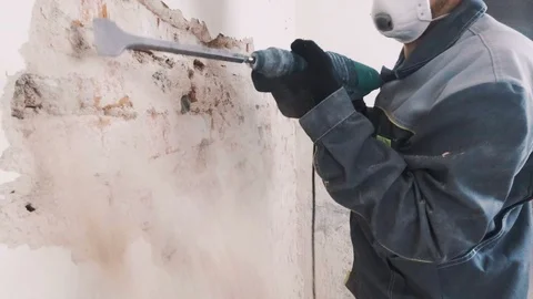 Worker in protective suit demolishes plaster wall. Dirty, hard work. Personal Stock Footage