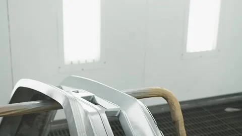 Worker in a protective suit with a mask paints car parts in a special enclosed Stock Footage 259243458