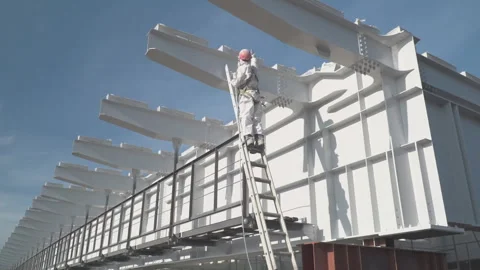 The worker in a protective suit paints with white paint building constructions Video stock 316590384