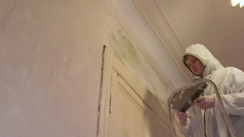 Worker in protective suit putting the walls spatula spread motion repair Stock-Footage 147655370