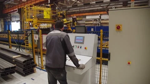 Worker in protective uniform operates the robotic machinery welding steel parts Stock Footage 202049797
