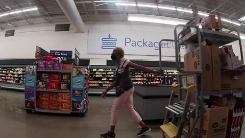 Worker pulling a cart wearing face mask Walmart retail store interior Stock Footage 157931413