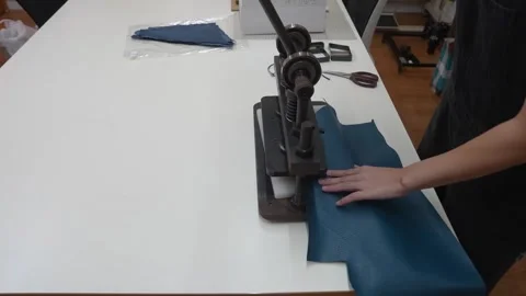 Worker pulls lever on manual arbor press to cut leather piece Stock Footage 339642840