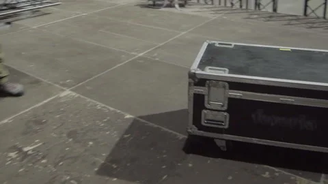 Worker pushes wheeled equipment case during venue setup Stock Footage 326989840