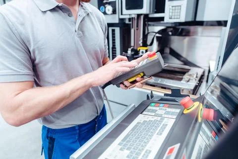 Worker pushing button to operate machine tool in manufacturing line Stock Photos