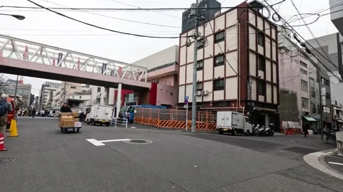 Worker Pushing Delivery Cart Across Urban Street in Tokyo Stock Footage 341905420