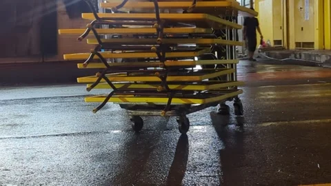 Worker Pushing Heavy Metal Cart in Rainy Outdoor Parking lot. Stock-Footage 329033976