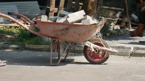 A worker is pushing a stroller filled with paving blocks Stock Footage 157412364
