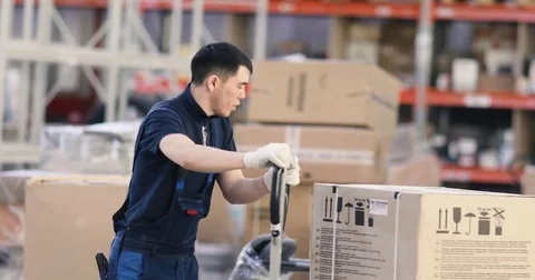 Worker pushing trolley with boxes in warehouse Stock Footage 84881460
