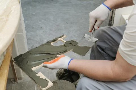 Worker puts the adhesive on the tile. Stock Photos