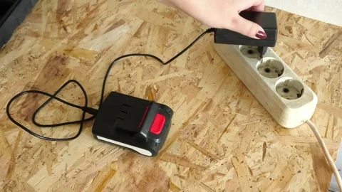 The worker puts the battery for the power drill to charge. Hands connect the Video stock 322894783