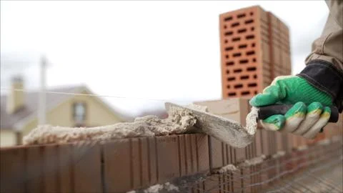 Worker puts a brick wall. Bricklayer working in construction site of a brick  Stock Photos