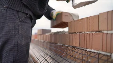 Worker puts a brick wall. Bricklayer working in construction site of a brick  Foto stock