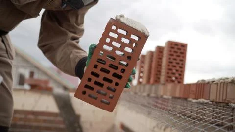 Worker puts a brick wall. Bricklayer working in construction site of a brick  Stock Photos