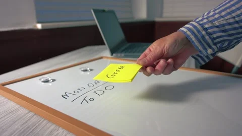 Worker puts coffee reminder note on Monday morning schedule whiteboard Video stock 338403854