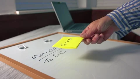 Worker puts coffee reminder note on Monday morning schedule whiteboard Stock-Footage 340133263
